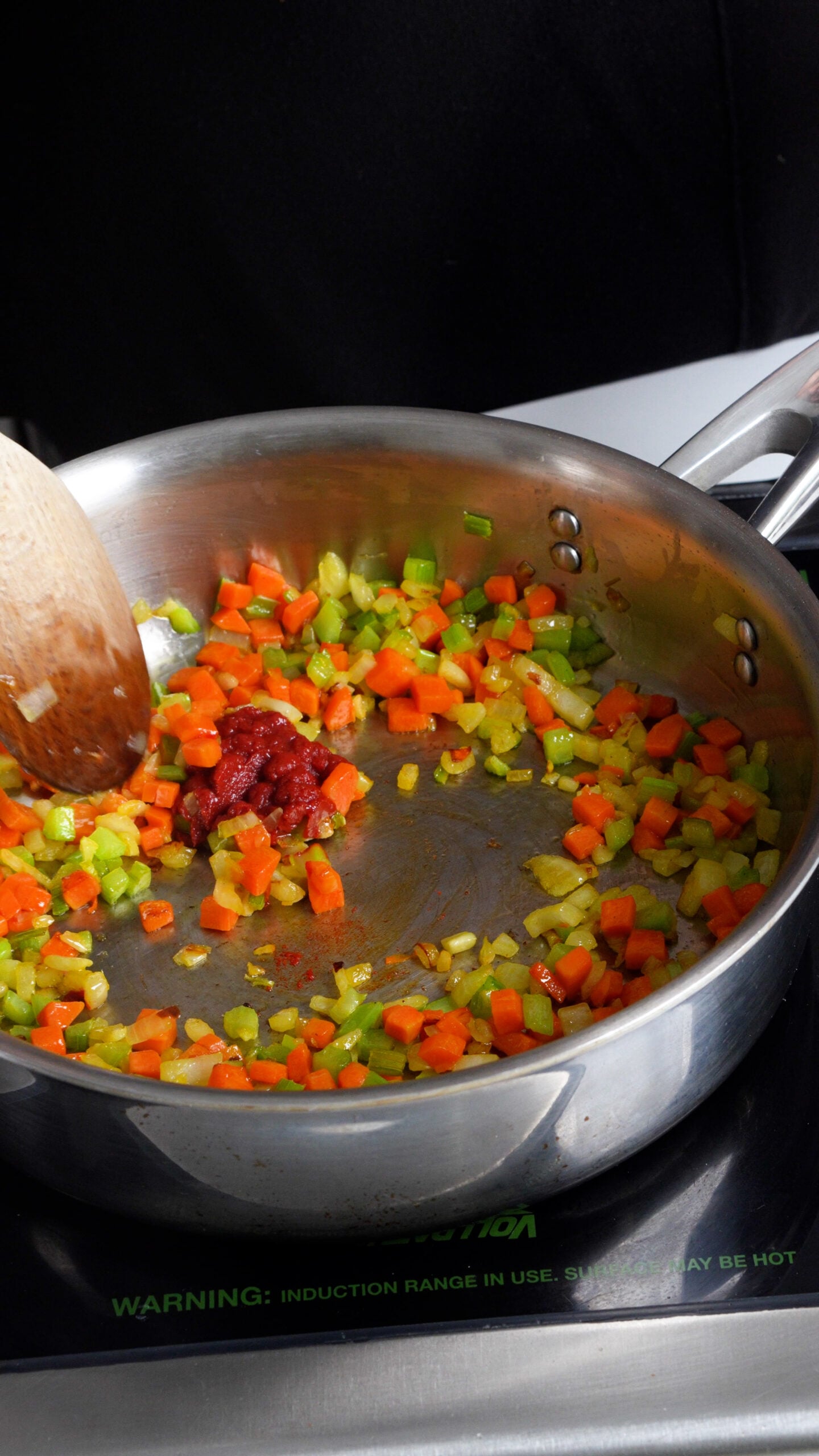 Small diced cooked carrot, celery and onion in a pan with a dollop of tomato paste