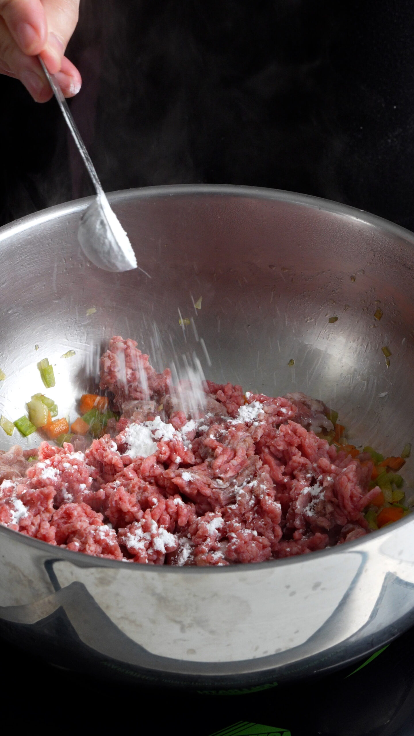 Sausage and ground beef in a pot with soffritto with corn starch being sprinkled on top