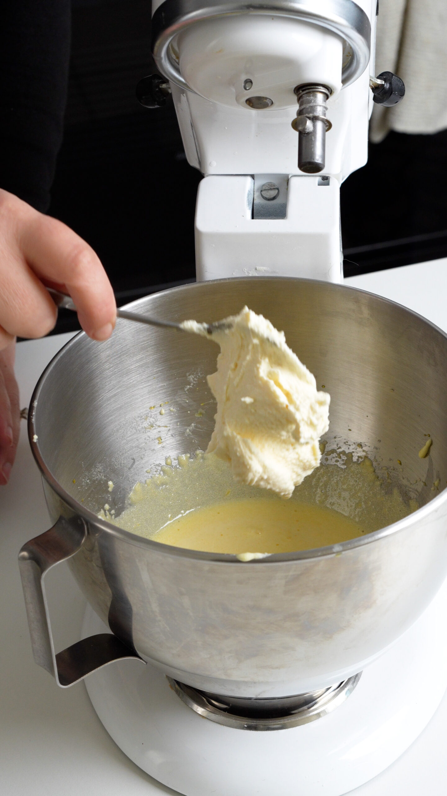 Mascarpone being added to egg yolks and sugar in a stand mixer