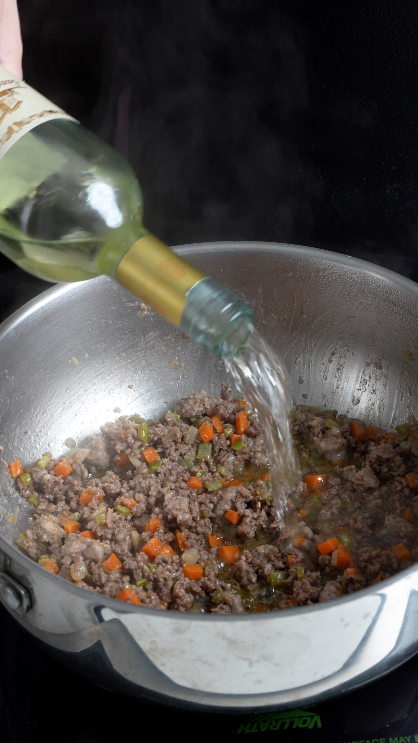 Ragu bianco in a pot being deglazed with white wine