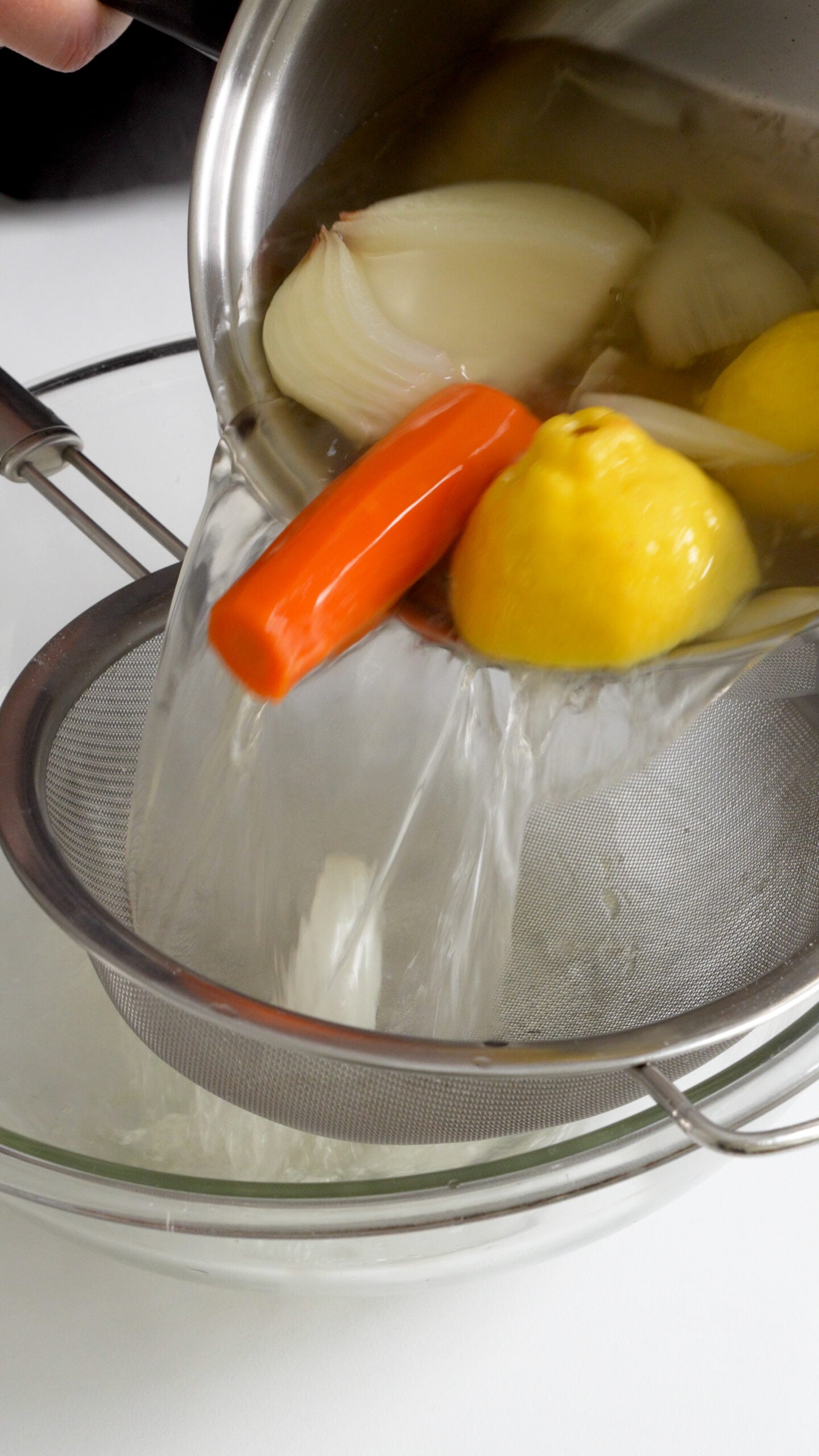 Lemon broth being strained into a bowl