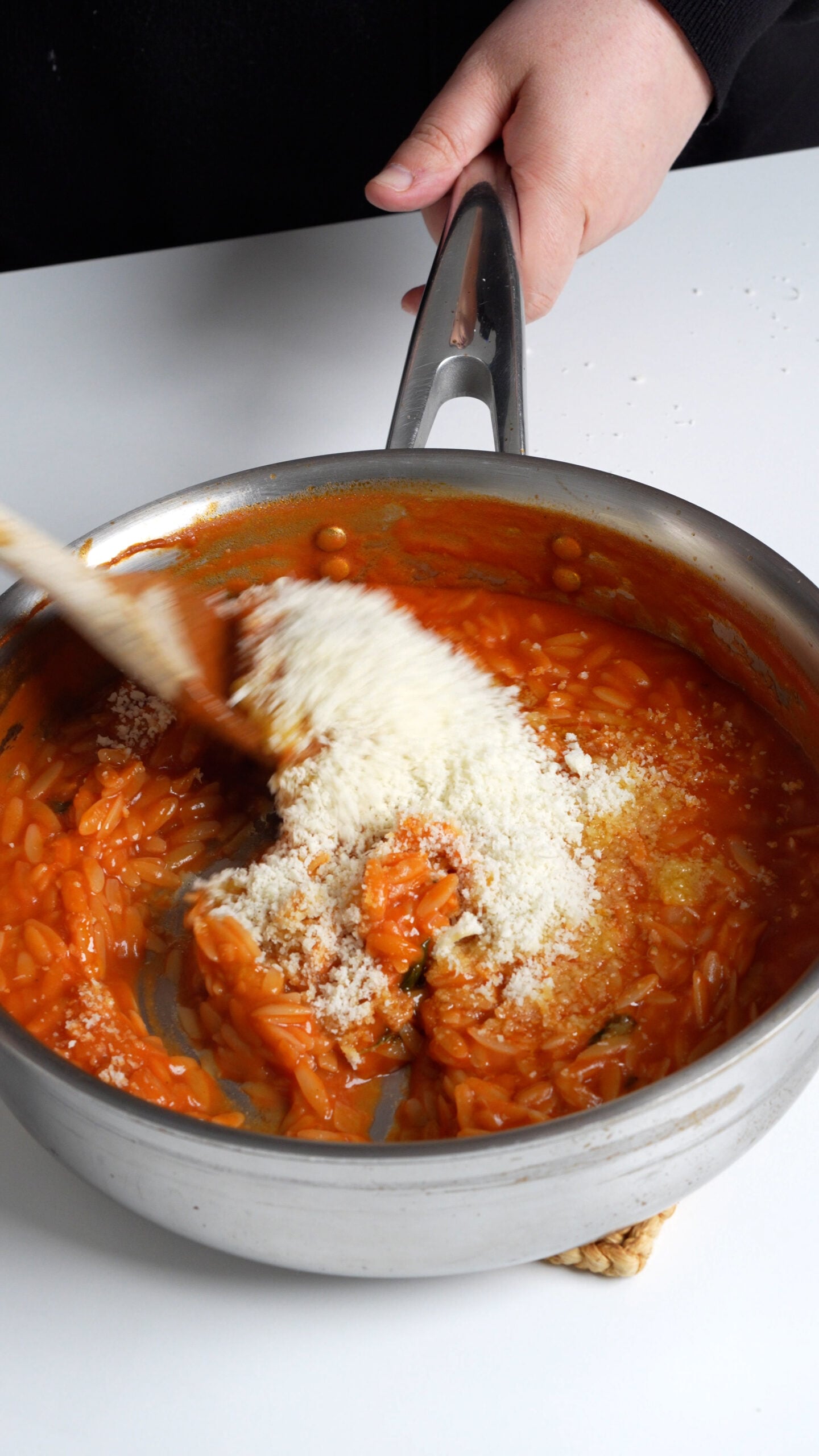 Tomato pastina being stirred in a pan with parmigiano reggiano