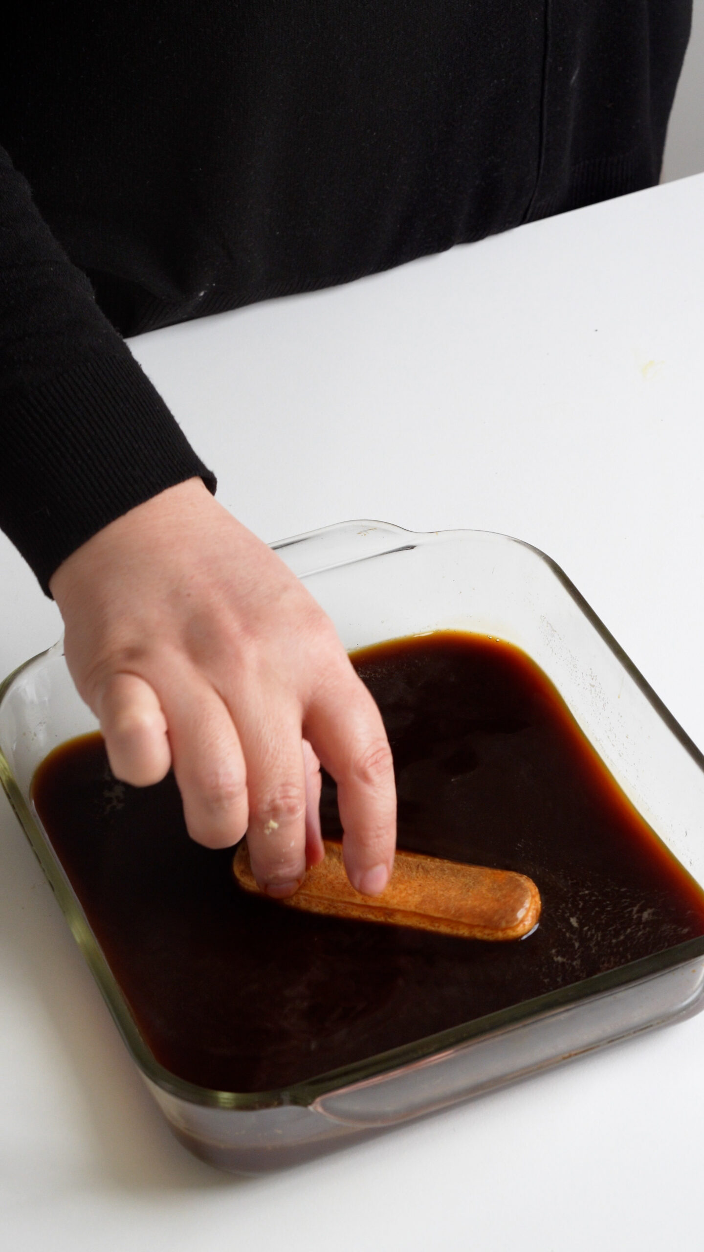 Ladyfinger cookies being dipped into espresso