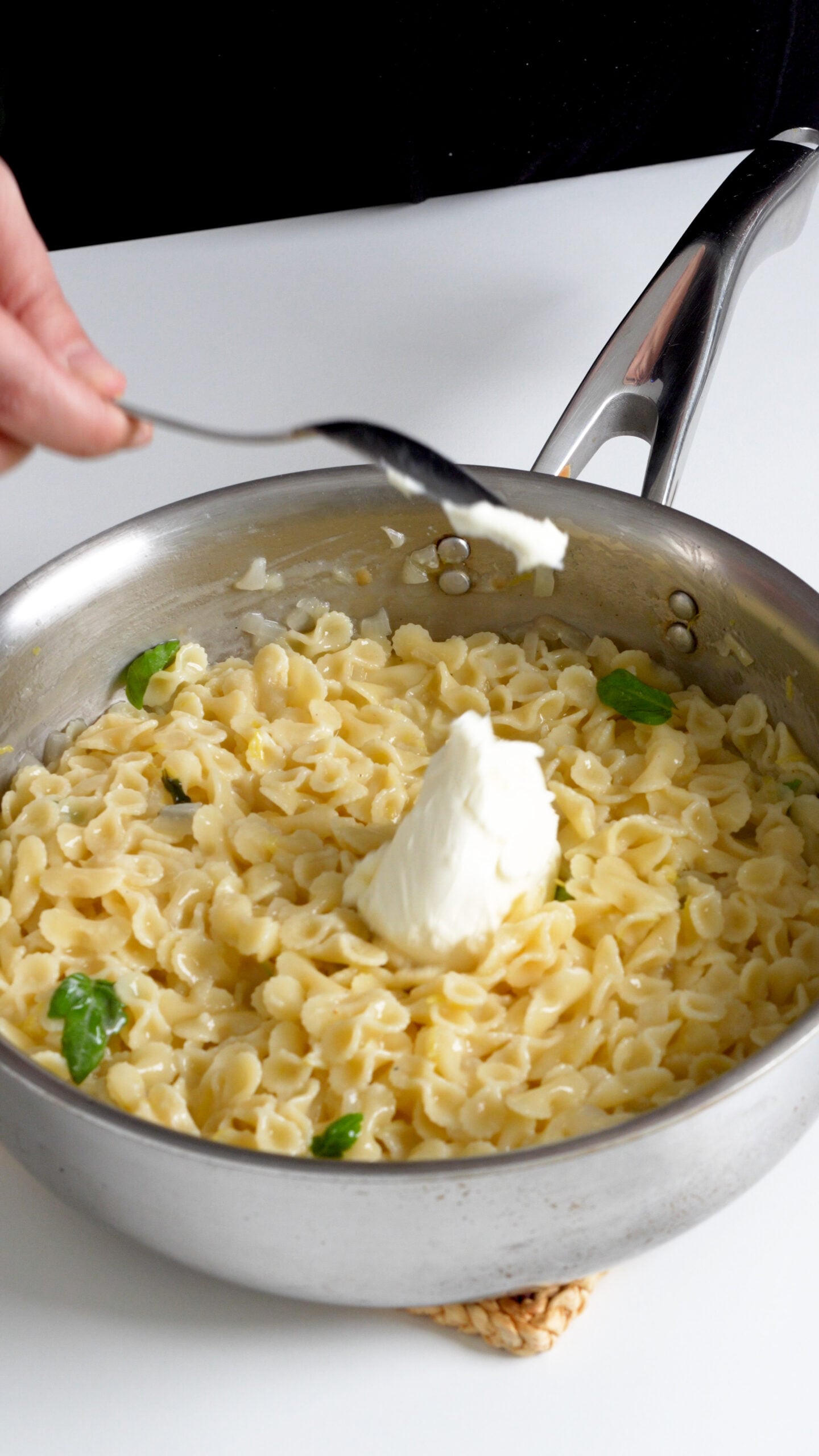 Mascarpone being added to a pan a pasta al limone