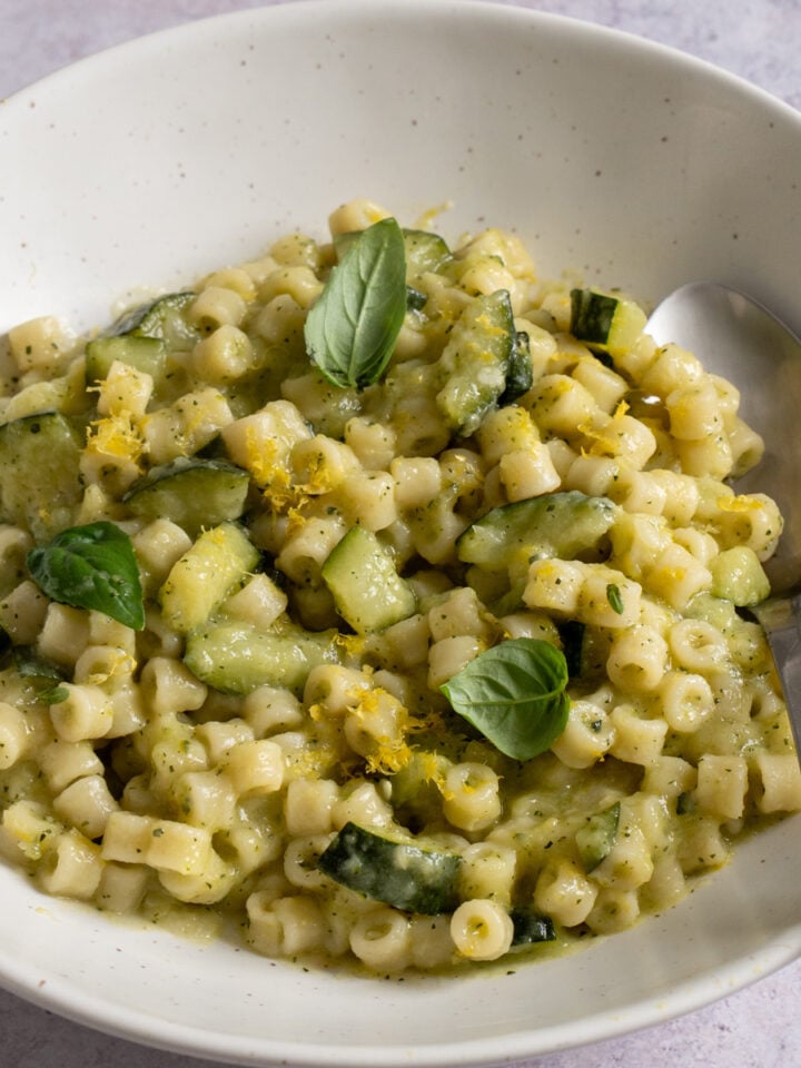 Pasta with zucchini in a bowl with a spoon to the side