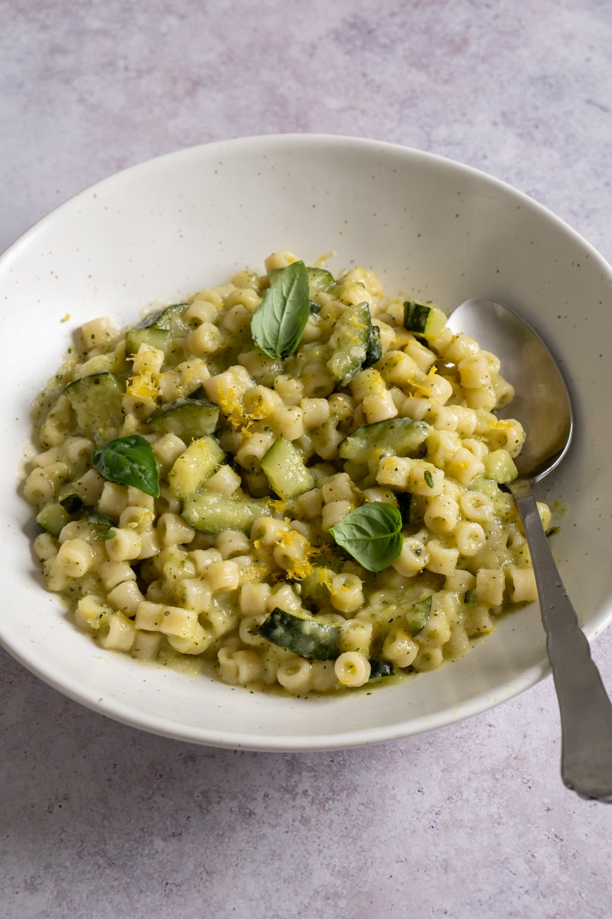 Pasta and zucchini in a bowl topped with fresh basil