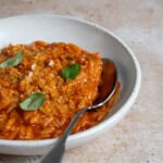 Tomato pastina in a bowl topped with fresh basil leaves