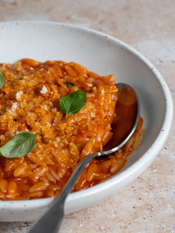 Tomato pastina in a bowl topped with fresh basil leaves