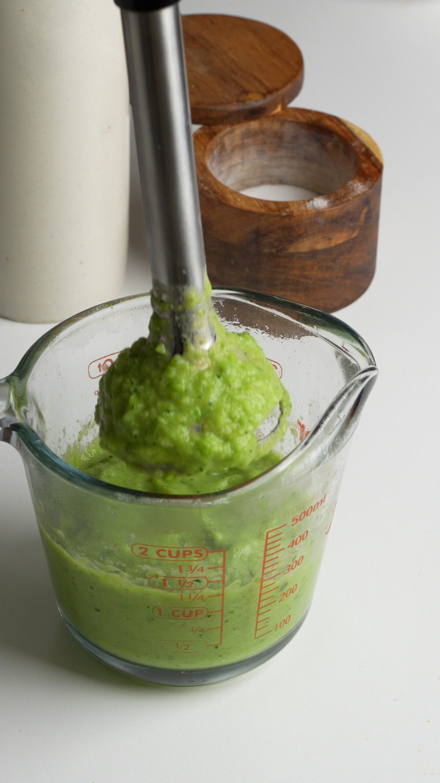 Zucchini and peas being blended with an immersion blender