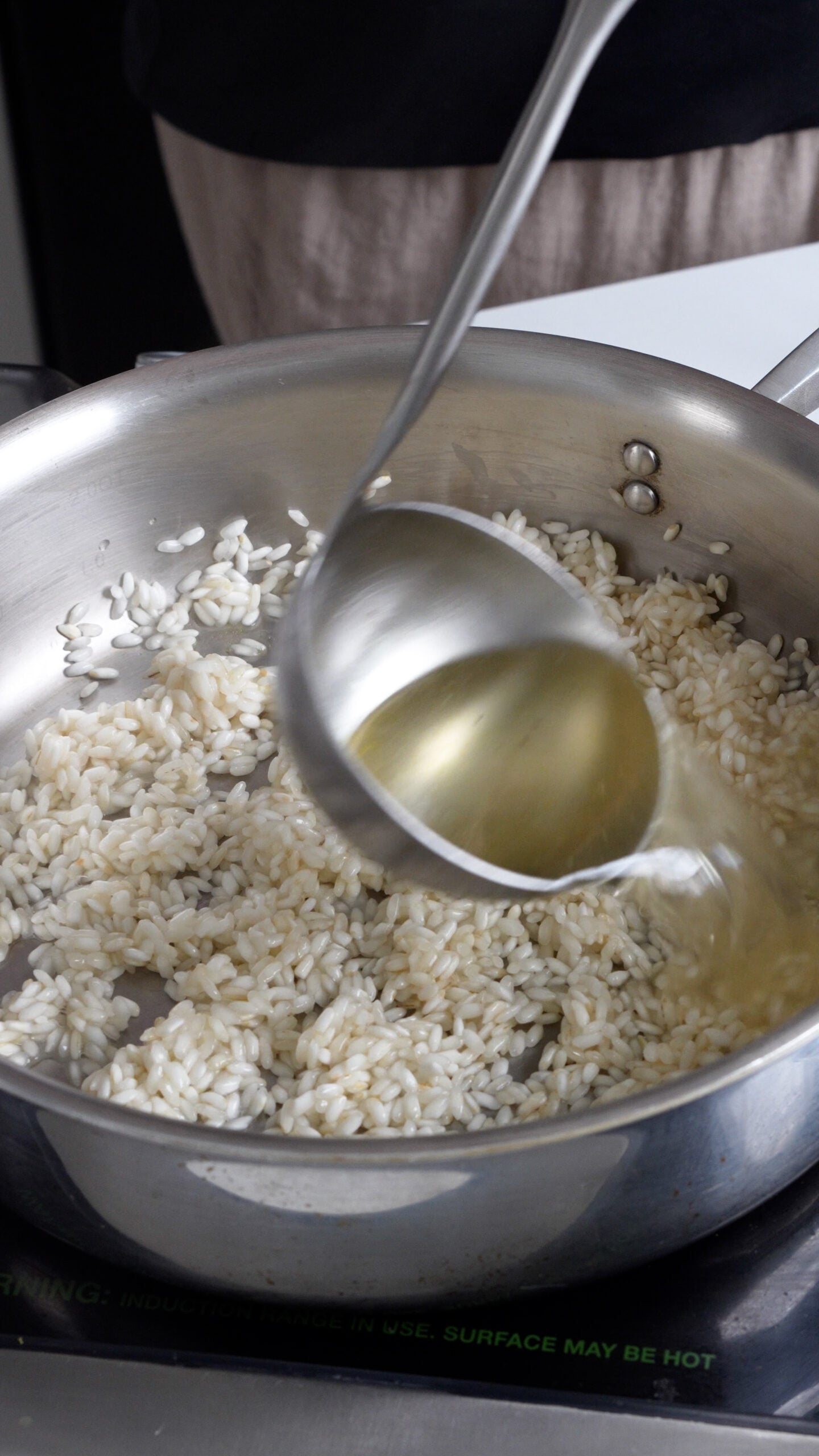 Vegetable stock being poured into a pan with rice in it
