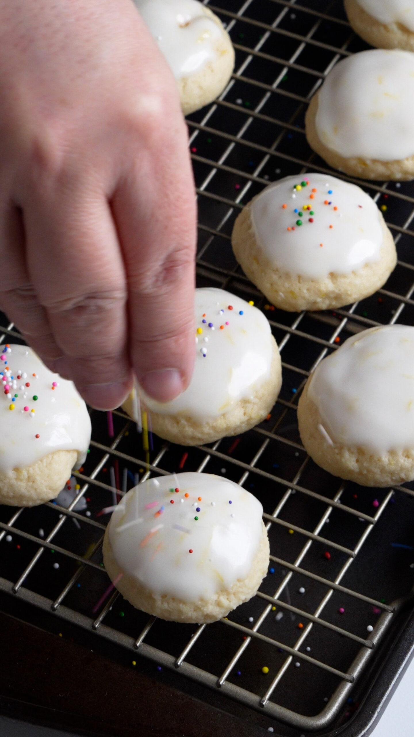 Sprinkles being sprinkled onto cookies