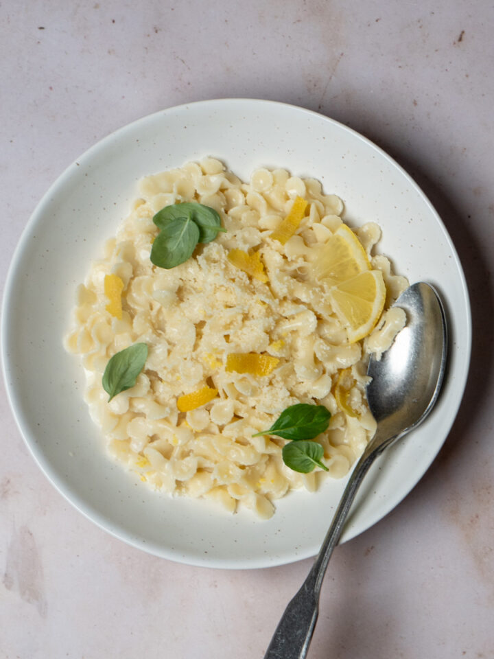 Plate of pasta al limone topped with fresh basil and grated parmigiano