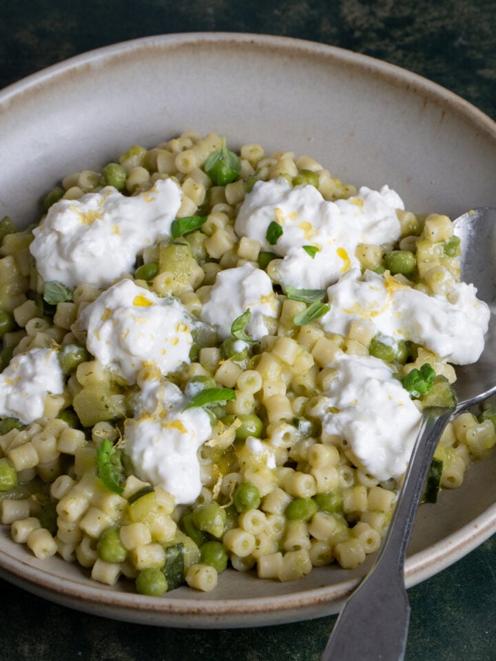 pasta piselli e zucchine topped with stracciatella chese and lemon zest