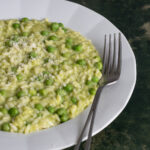 Risotto with peas in a plate topped with gratd parmigiano reggiano
