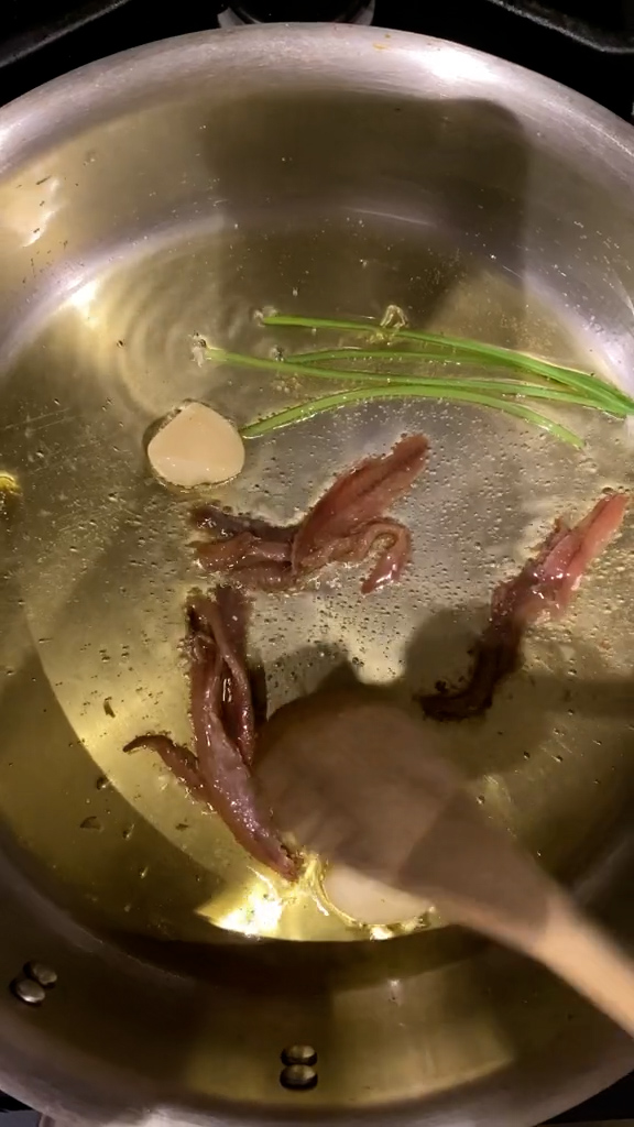 Olive oil, parsley stems, garlic clove and anchovies in a pan