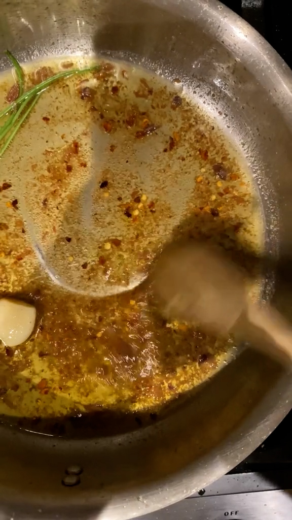 Melted anchovies, parsley stems, garlic clove, olive oil, and chili pepper flakes in a pan