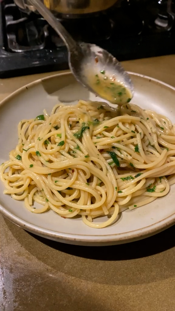 Spaghetti in a plate being topped with anchovy sauce