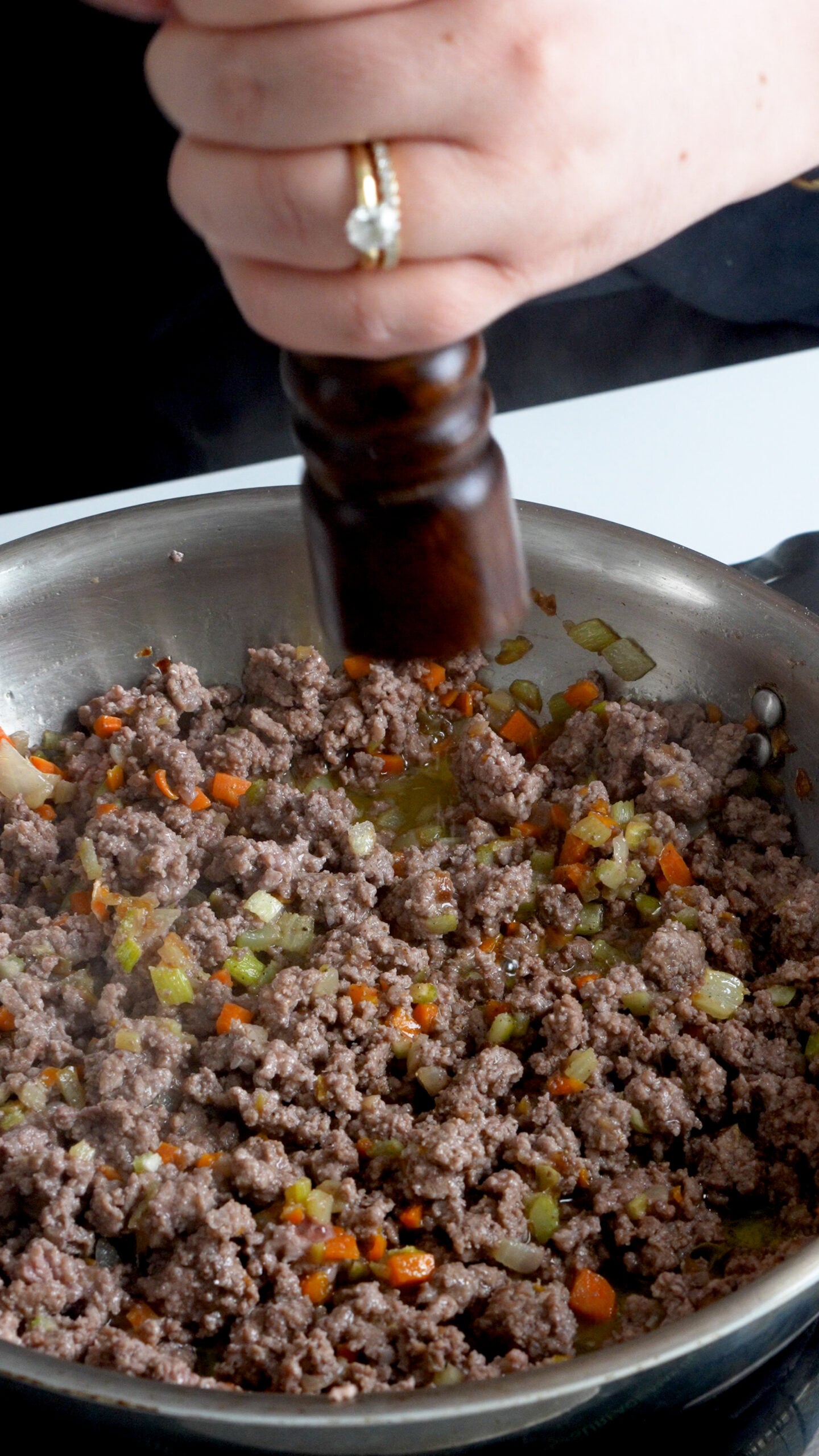 Cooked ground beef in a pan with chopped carrots, celery and onion