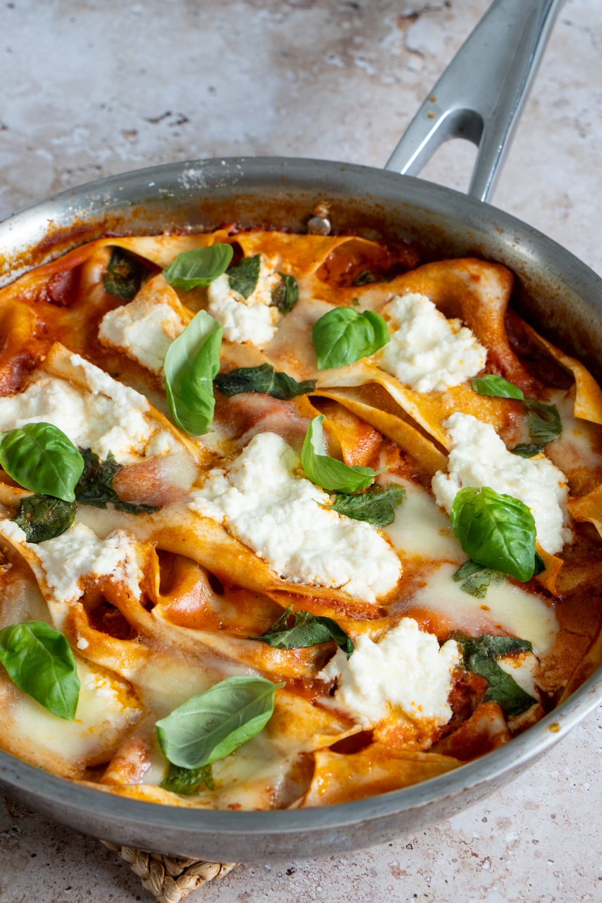 One pot lasagna in a pan topped with ricotta, mozzarella and fresh basil