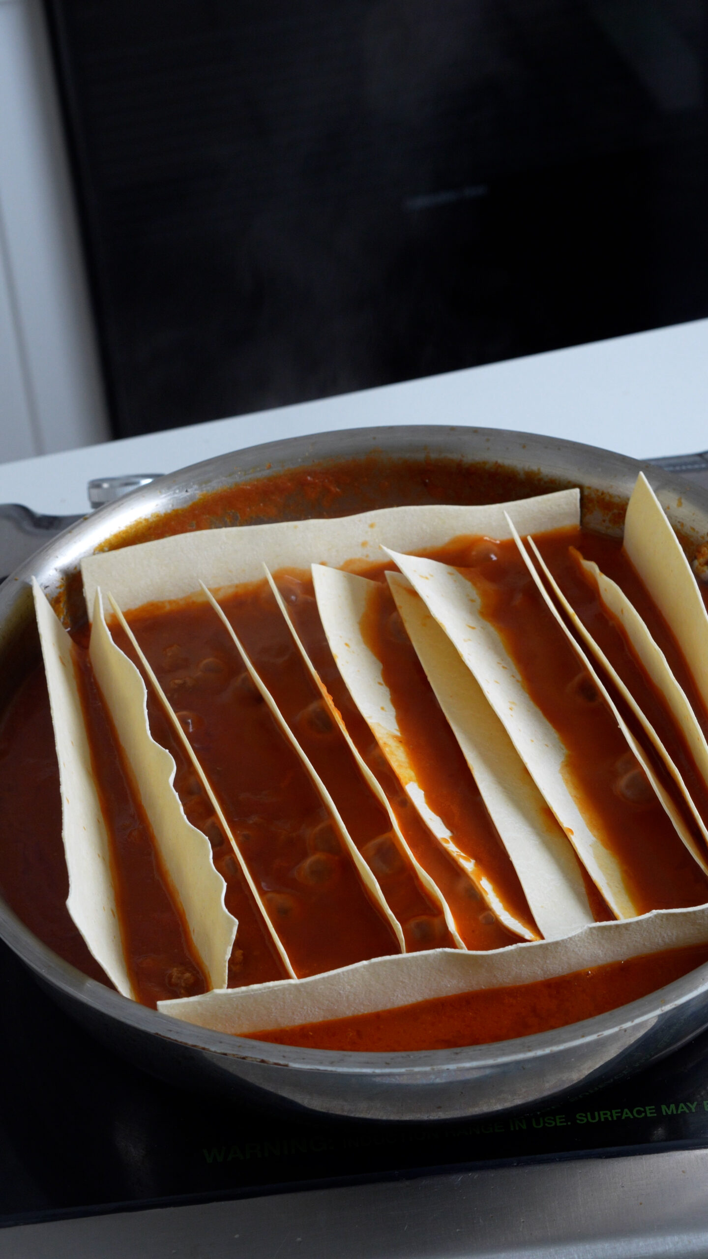 Lasagna sheets in meat sauce in a pan