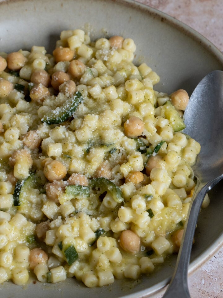 chick pea and zucchini pasta in a bowl with a spoon in it