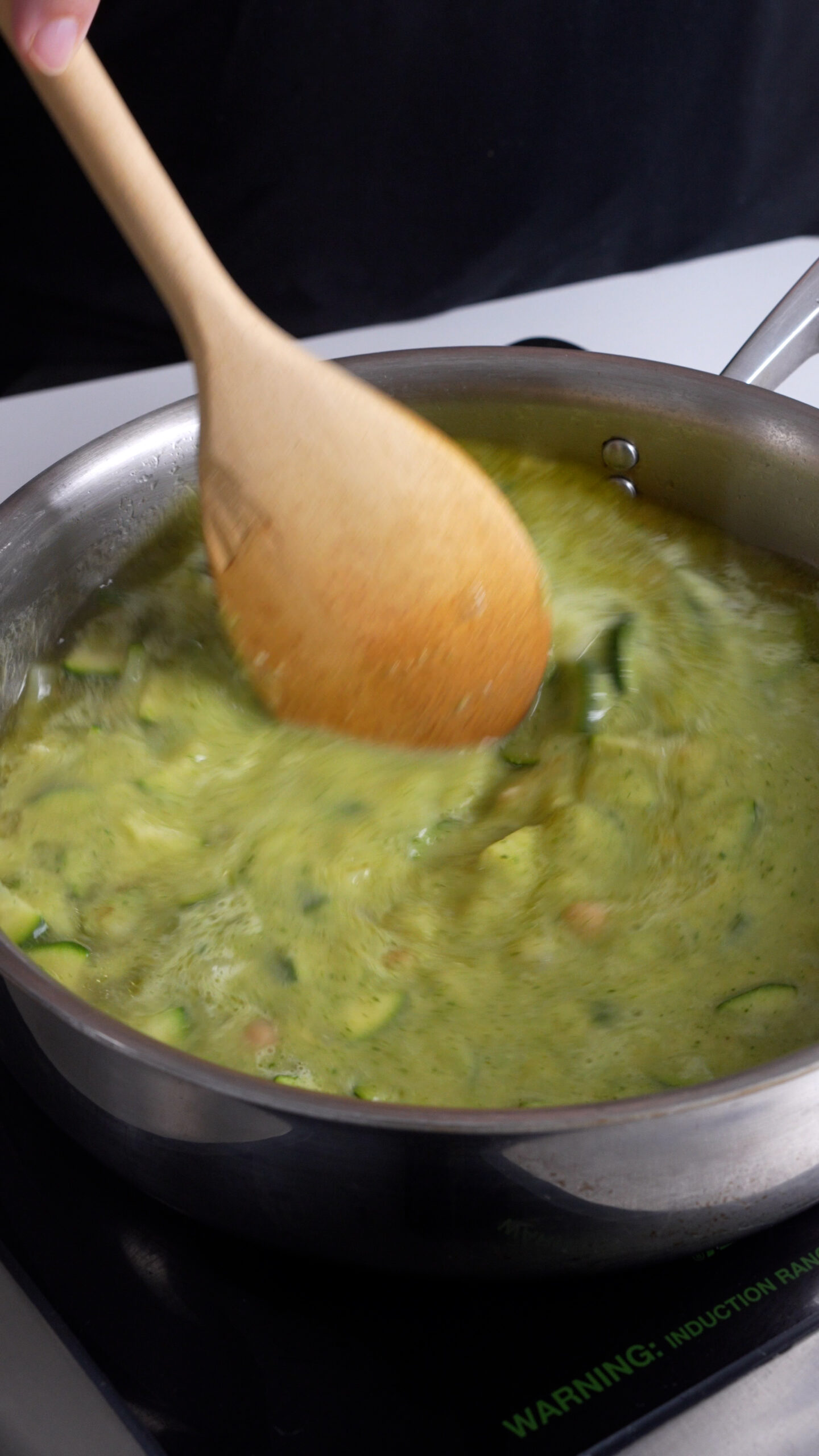 Zucchini and chick pea broth being stirred in a pan