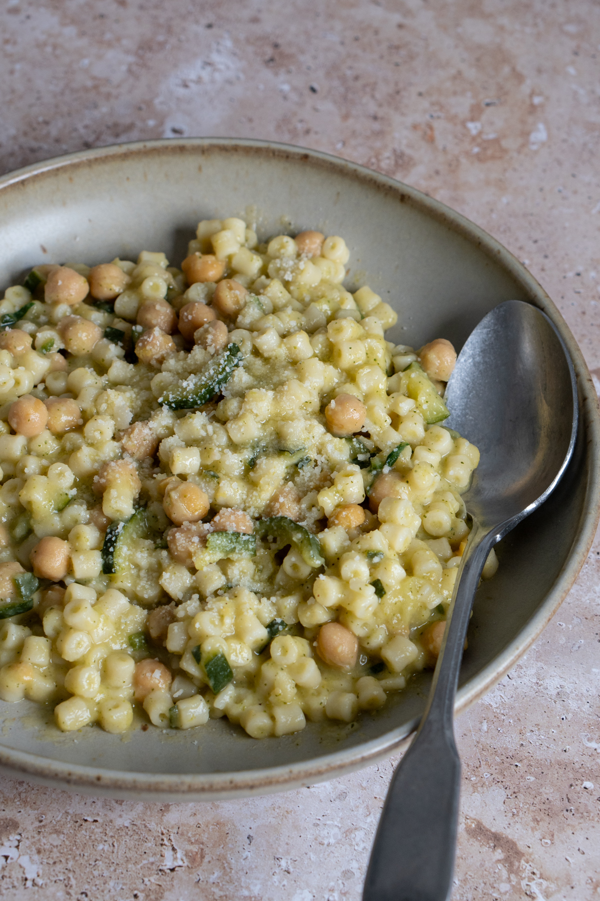 Chick pea and zucchini pasta in a bowl with a spoon to the side