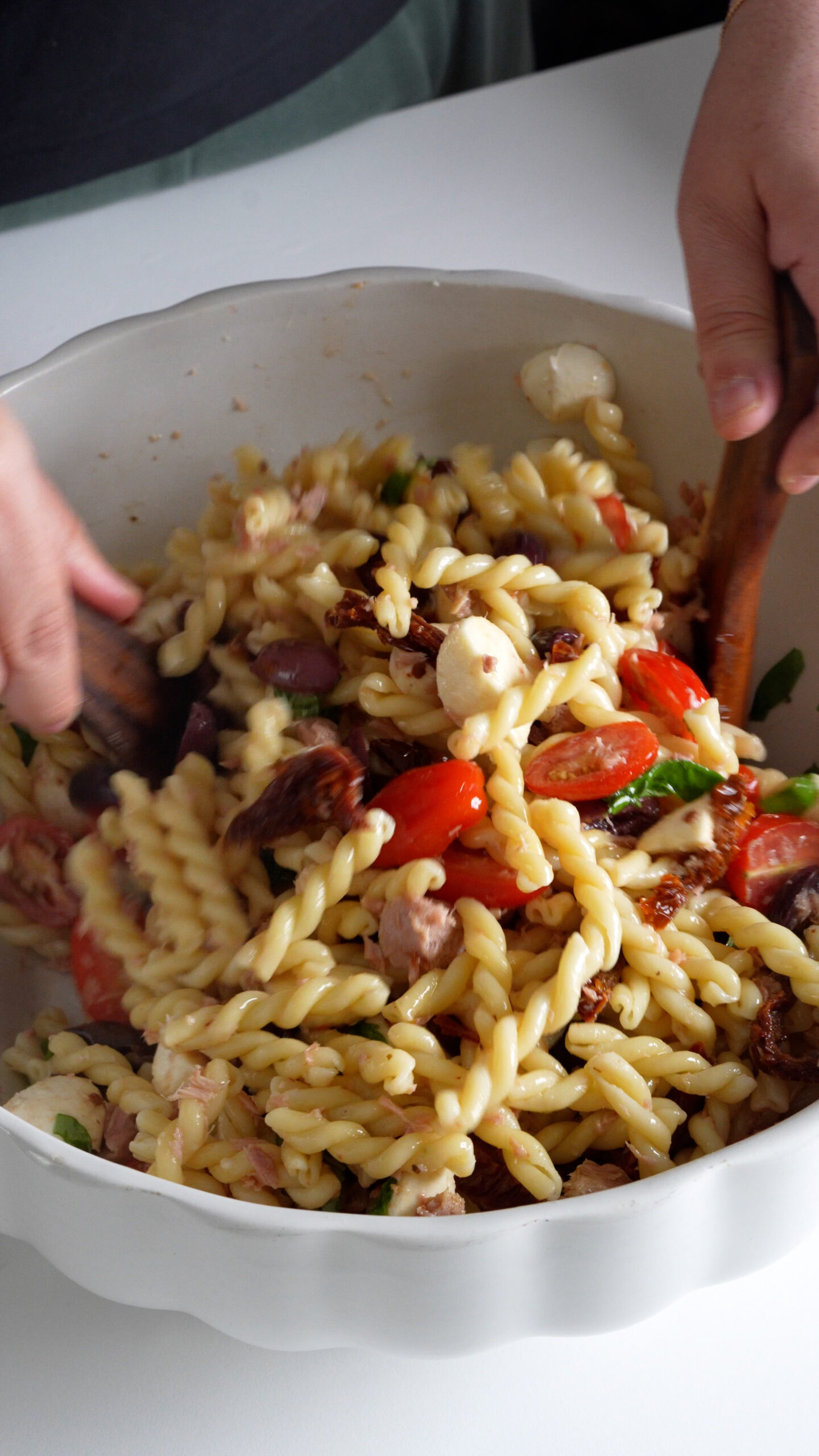 Pasta salad being mixed in a bowl