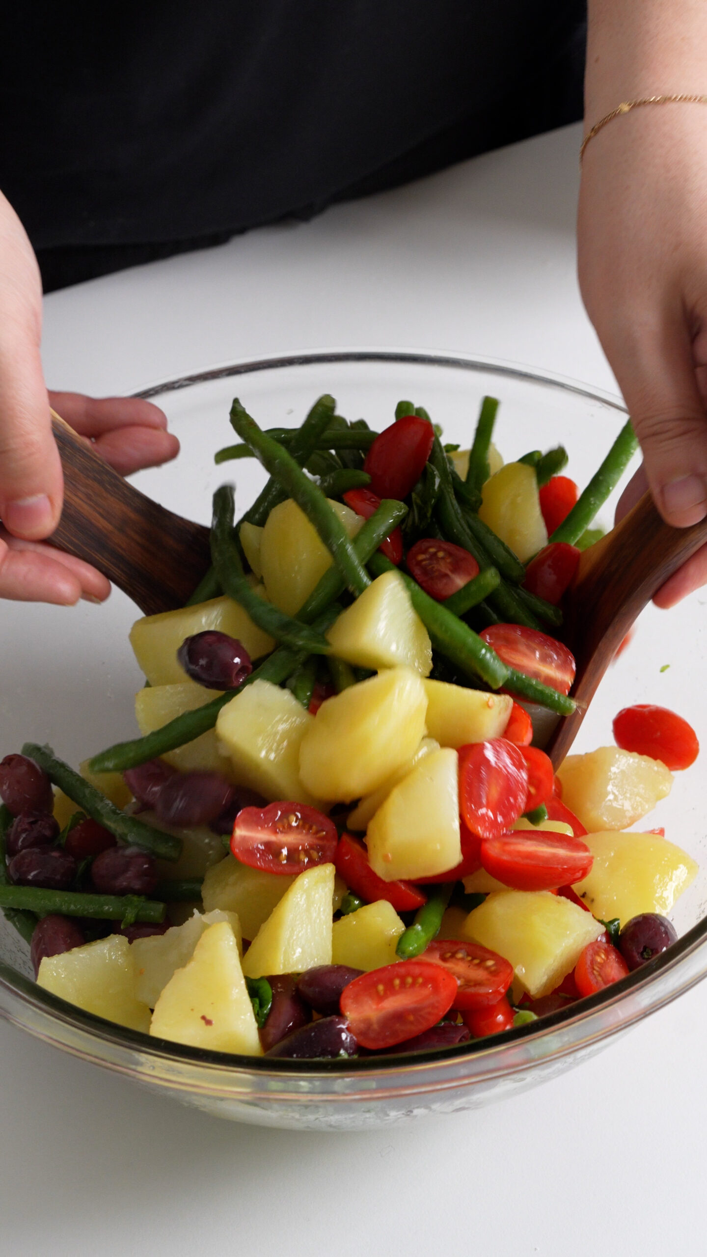 Potato salad with green beans being tossed in a bowl