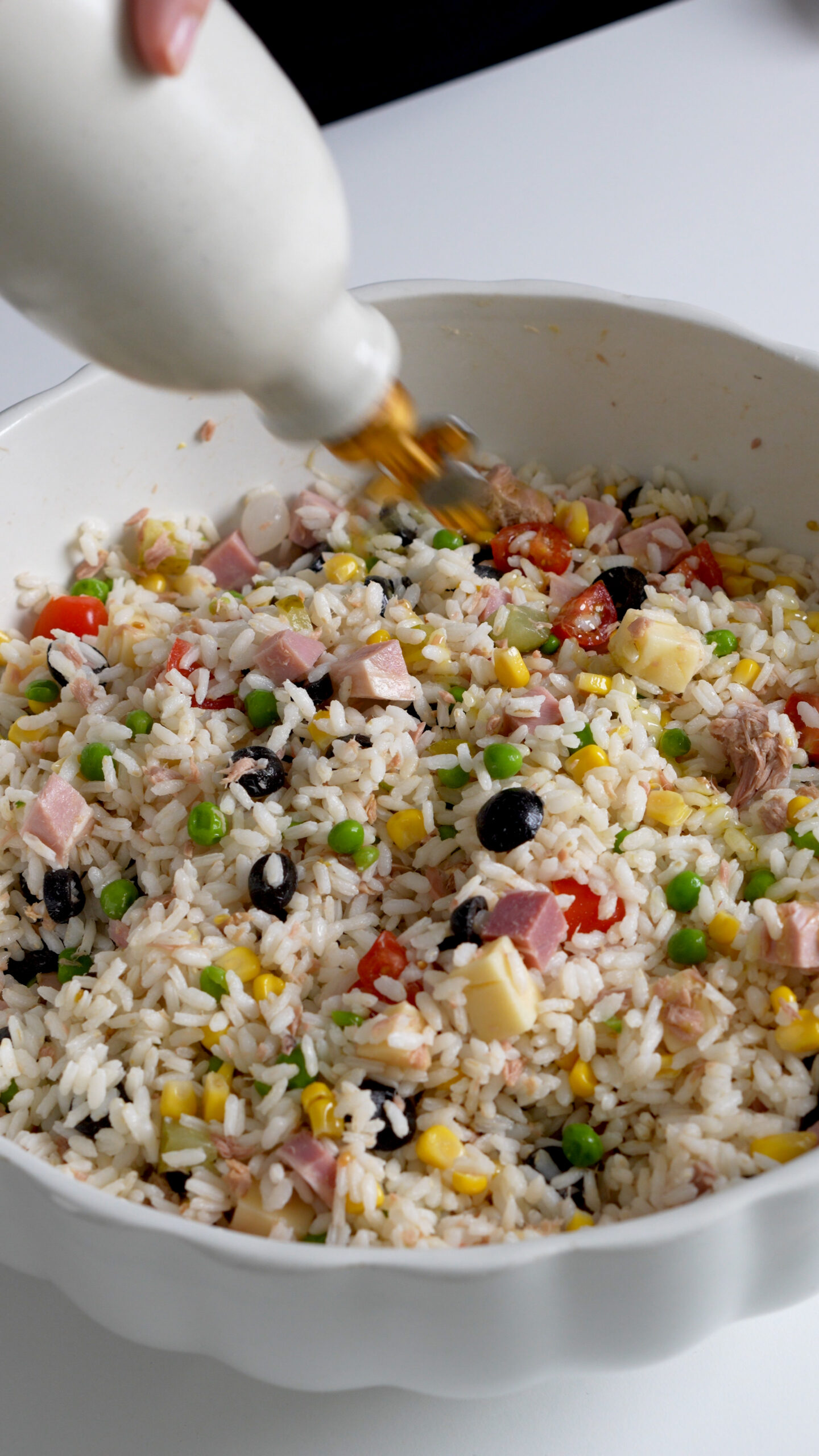 Rice salad in a bowl being drizzled with olive oil
