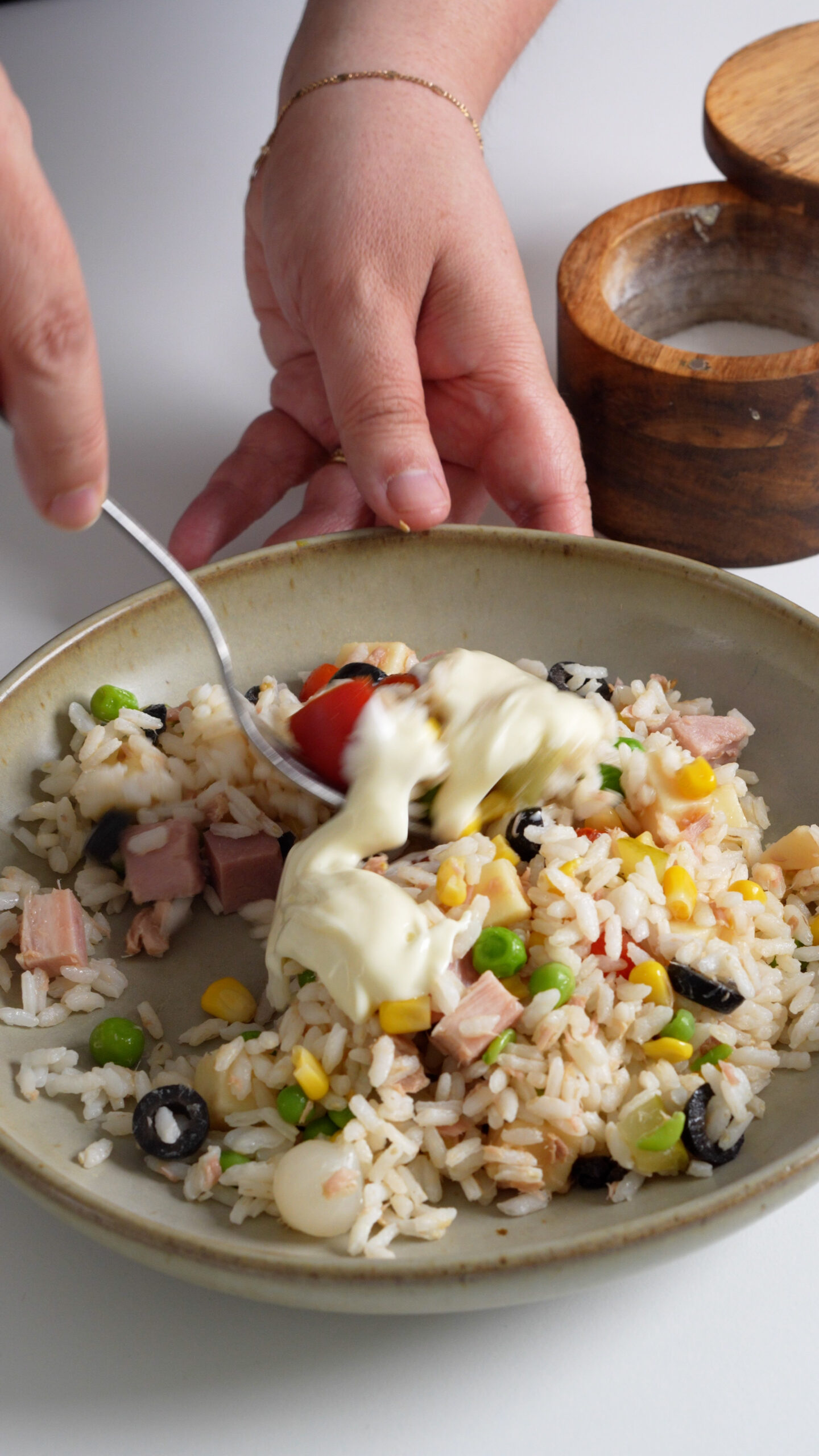 Rice salad in a dish being mixed with mayonnaise