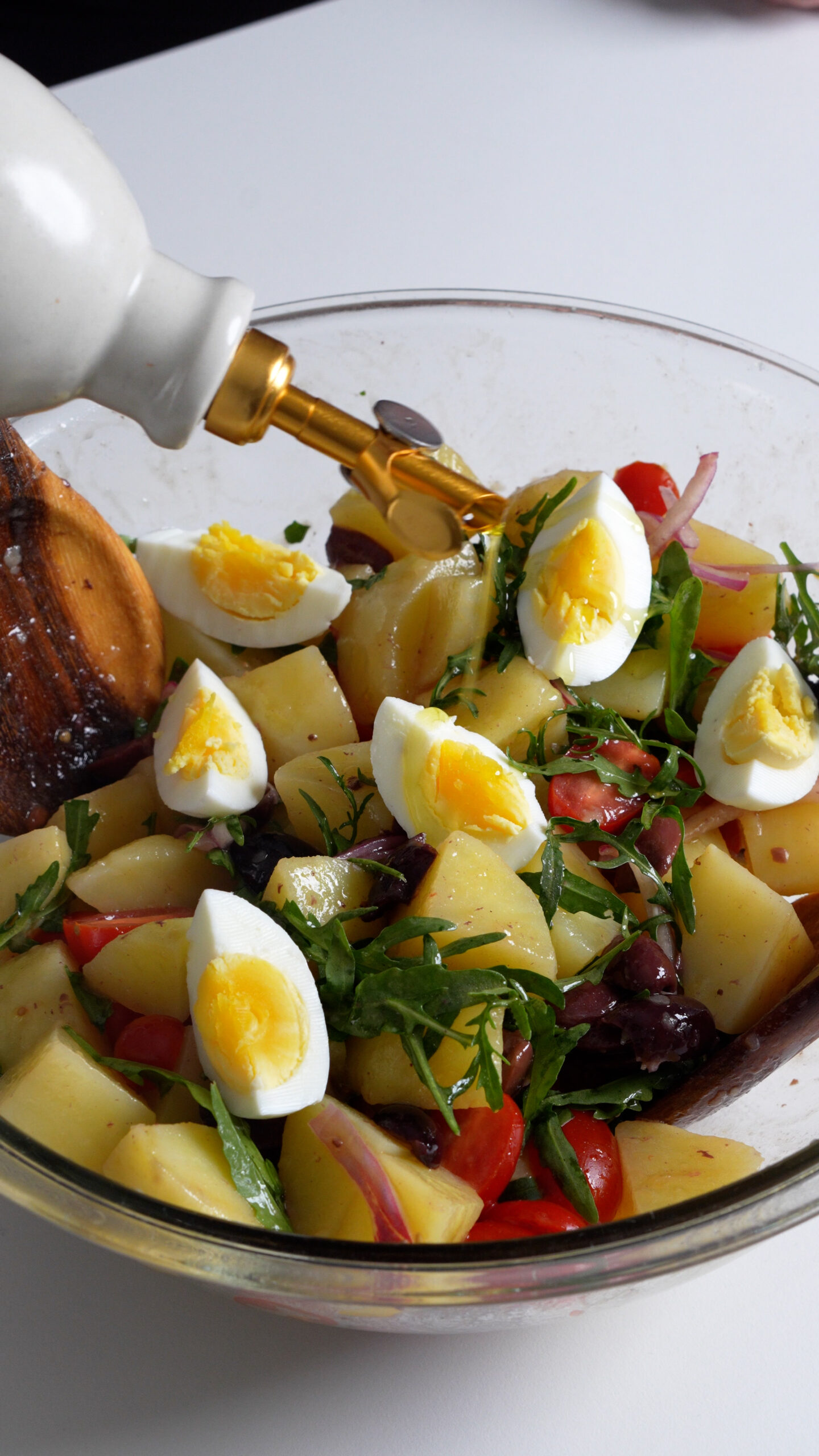 Italian potato salad with arugula, tomatoes, olives, onions, topped with hard boiled eggs