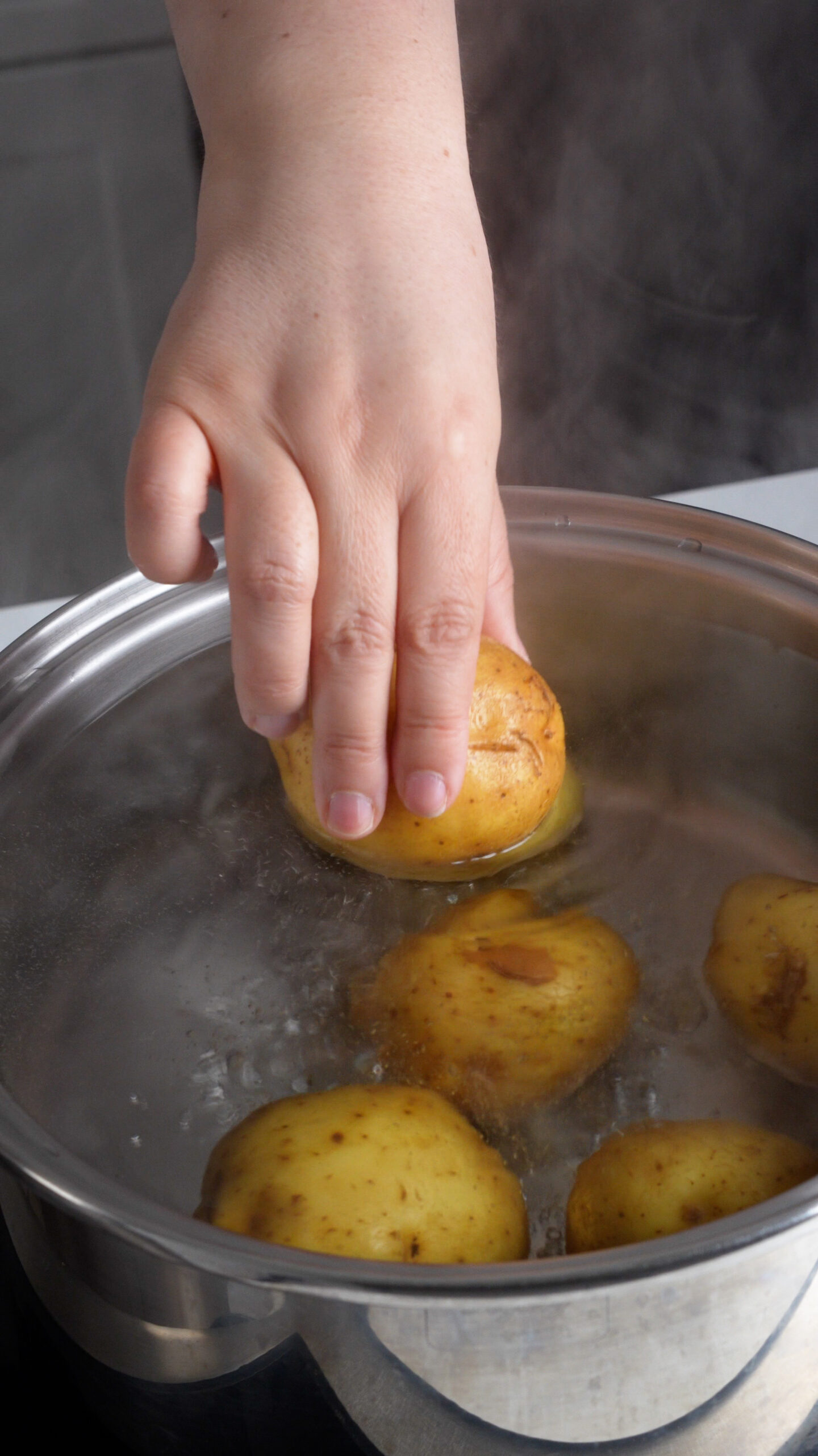Yukon gold potato being placed in boiling water