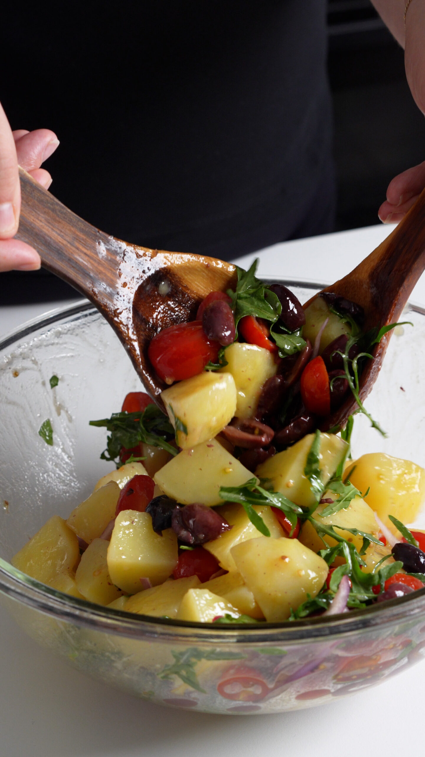Italian potato salad with arugula being mixed in a large bowl